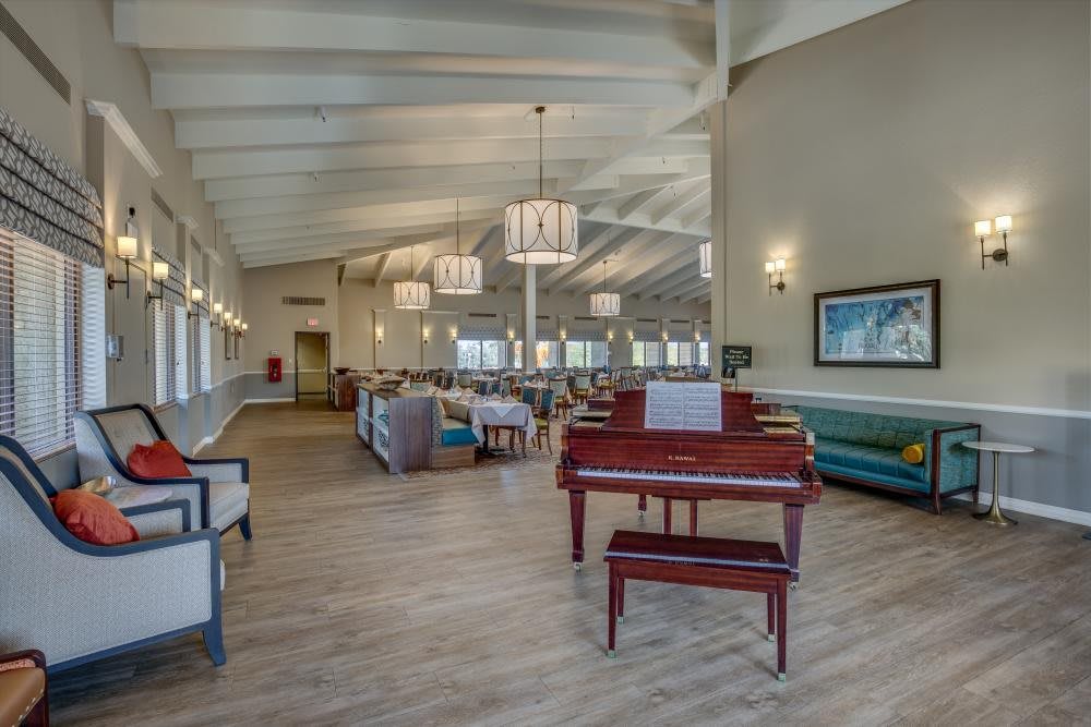 A spacious lounge area featuring a piano, comfortable seating, and elegant lighting.