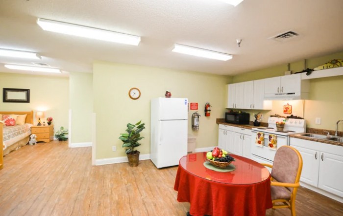 A modern kitchen and dining area with a refrigerator, table, and wooden flooring.