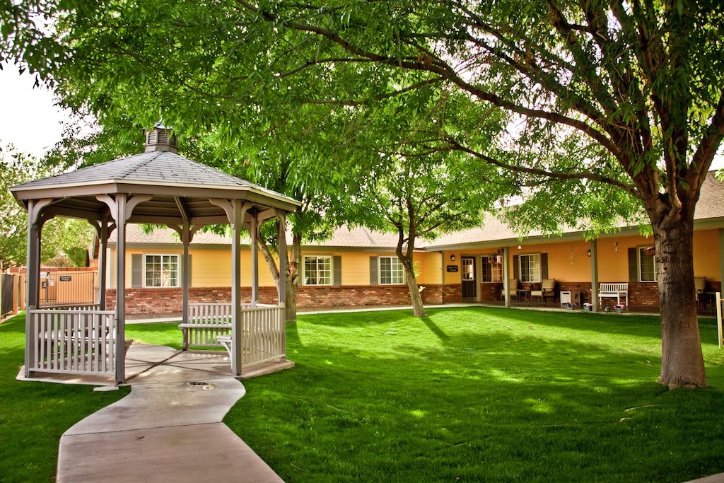 A peaceful courtyard with a gazebo, surrounded by a well-maintained lawn and trees.