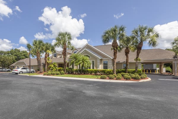 A residential building surrounded by palm trees under a partly cloudy sky.