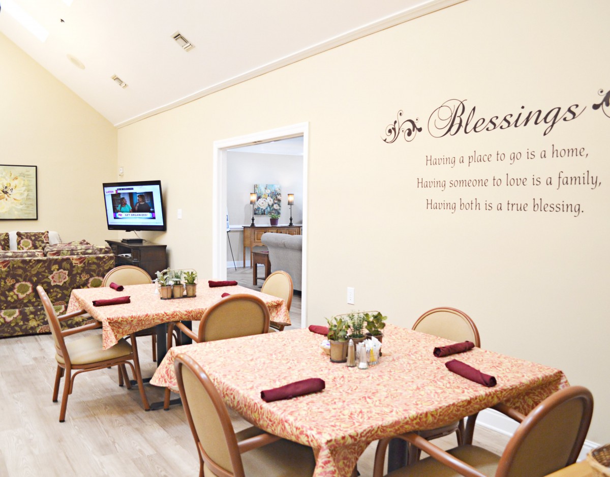 A cozy dining area with neatly arranged tables and chairs, decorated with plants and wall art.