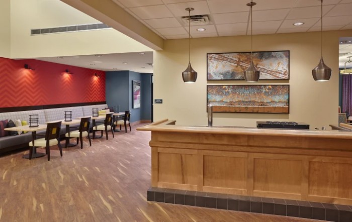 A modern reception area featuring a wooden counter and a comfortable waiting space with artwork and pendant lighting.