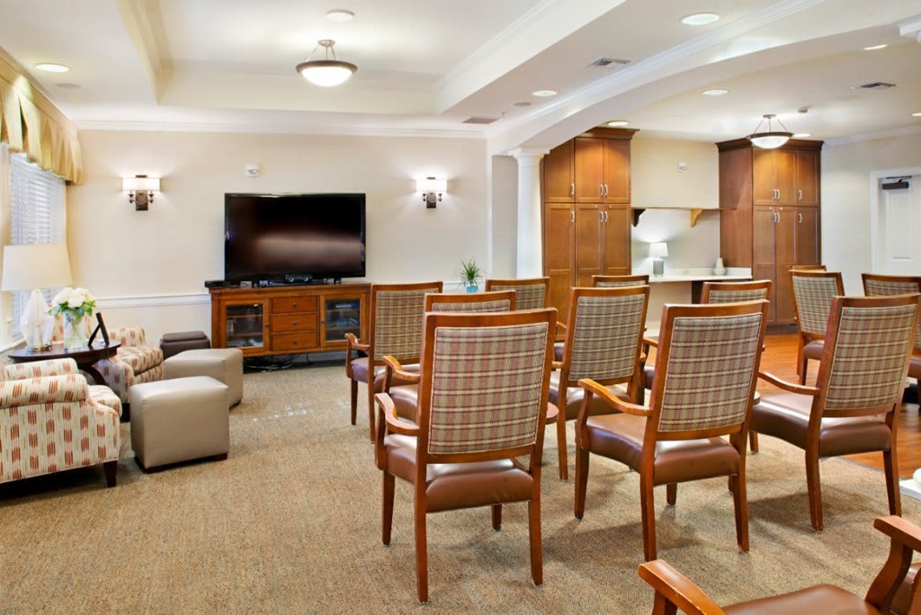 A comfortable meeting space featuring multiple chairs and a large television.
