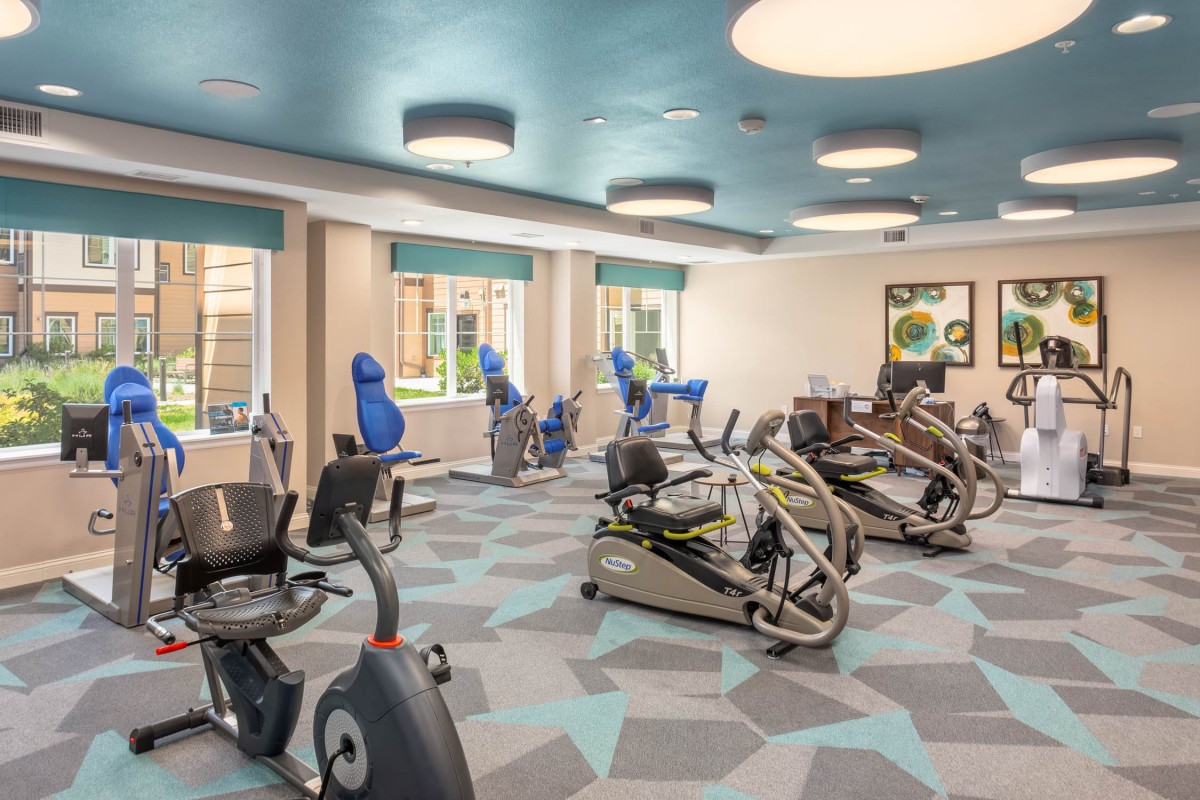 A modern gym with various exercise equipment including stationary bikes and cardio machines.