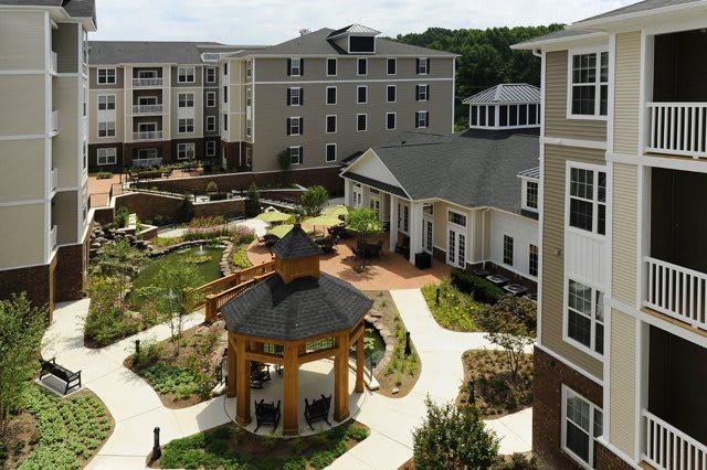 A well-landscaped apartment complex with a central gazebo and surrounding gardens.
