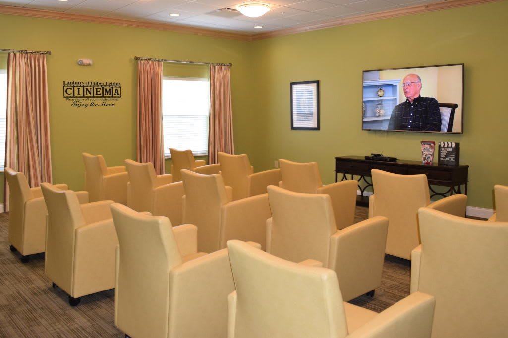 A small theater room with rows of chairs facing a television screen.