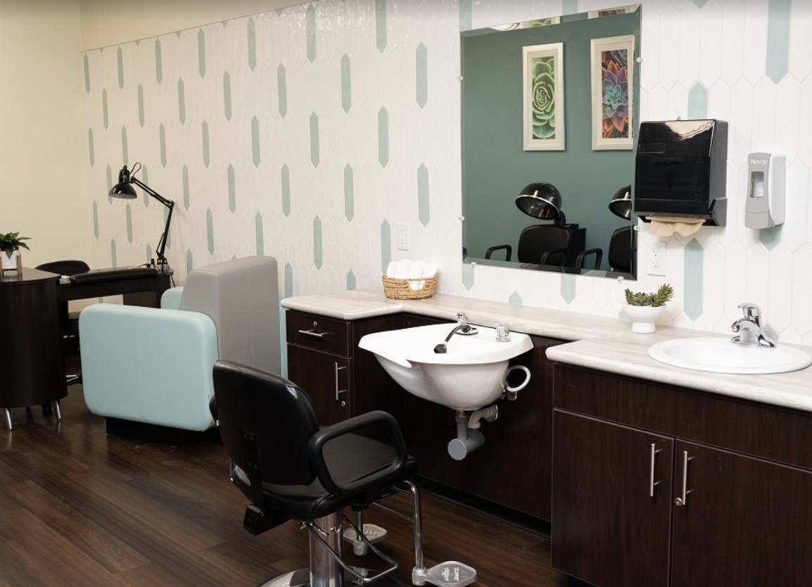 Modern hair salon interior with a styling chair, sink, and mirror.