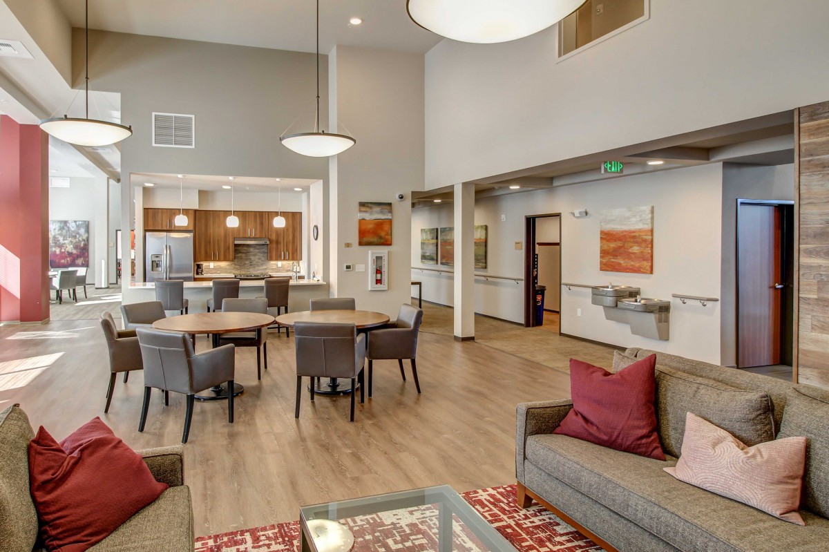 A modern living room with a dining area and kitchen, featuring stylish furniture and warm decor.