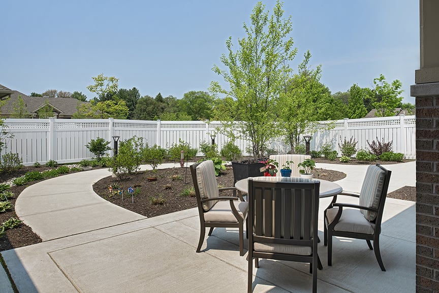 A cozy backyard patio with a table and chairs surrounded by a landscaped garden.