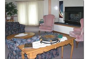 A cozy living room with a table, armchairs, sofa, and a fireplace.