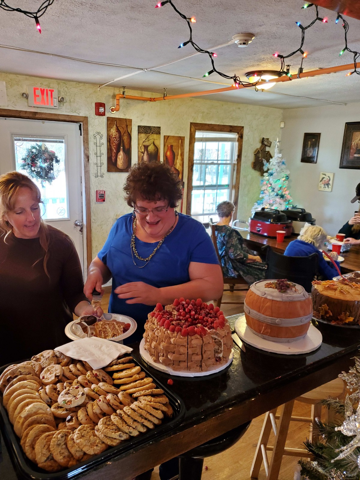 Two women serving desserts at an indoor gathering.