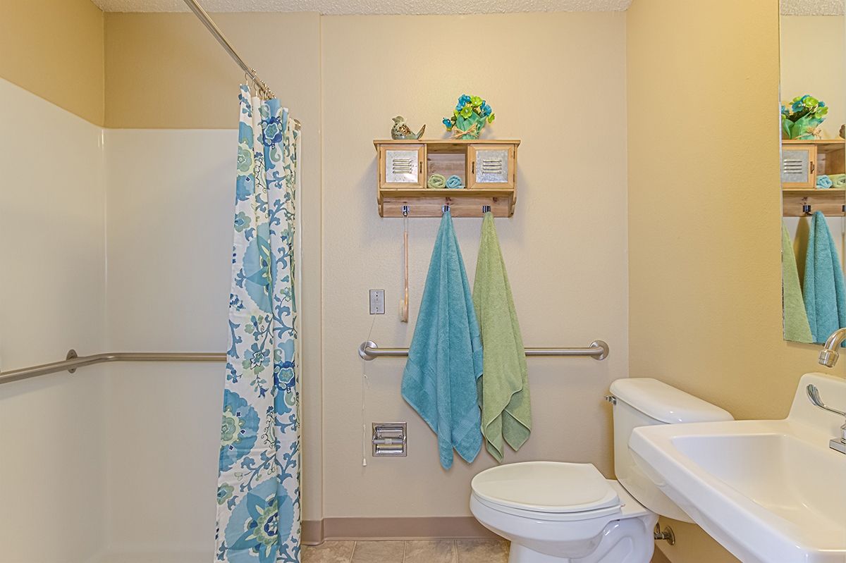A tidy bathroom featuring a toilet, colorful towels, and a vibrant shower curtain.