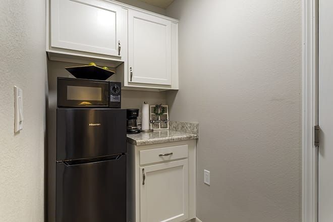 A small kitchen corner with a microwave, refrigerator, cabinets, and countertop.
