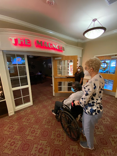 A woman assists another person in a wheelchair at the entrance of a restaurant.