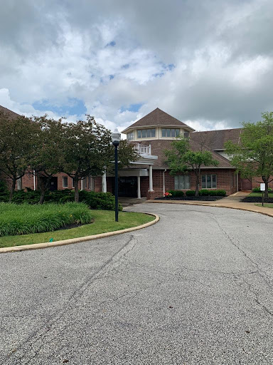 A serene view of a well-designed building surrounded by lush greenery and a winding pathway.