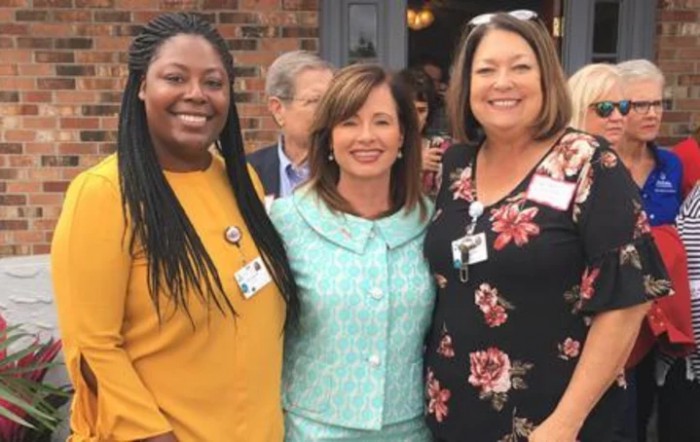 Three women smiling together at an event.
