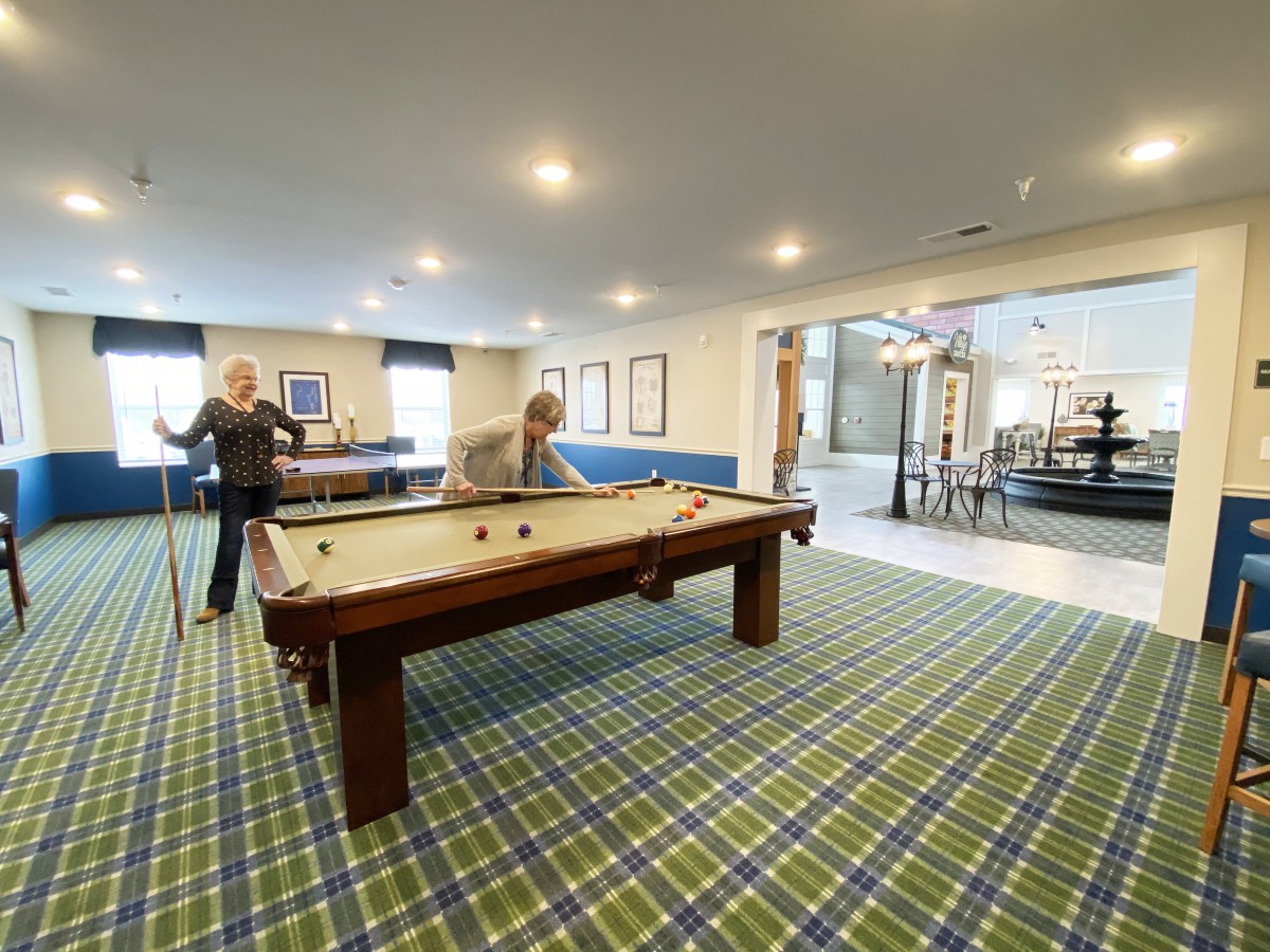 Two people enjoying a game of pool in a recreational room.