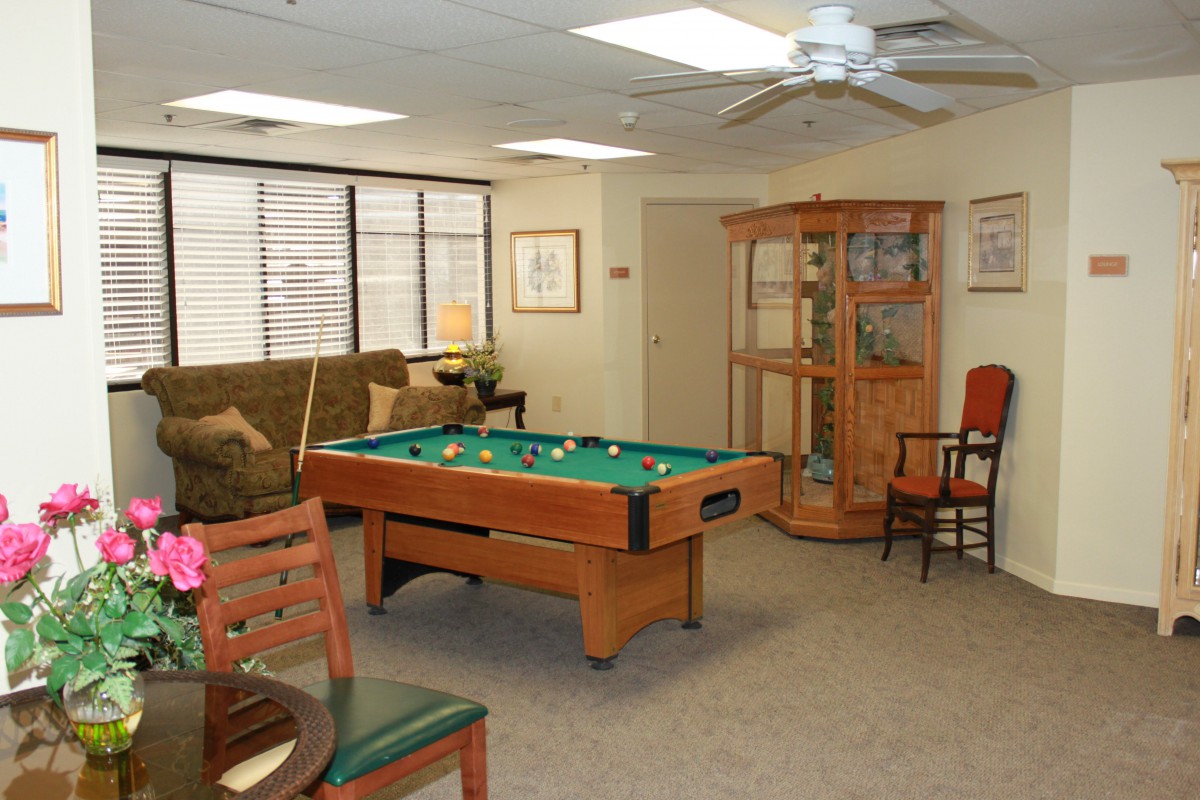 A cozy game room featuring a pool table, sofa, and various chairs.