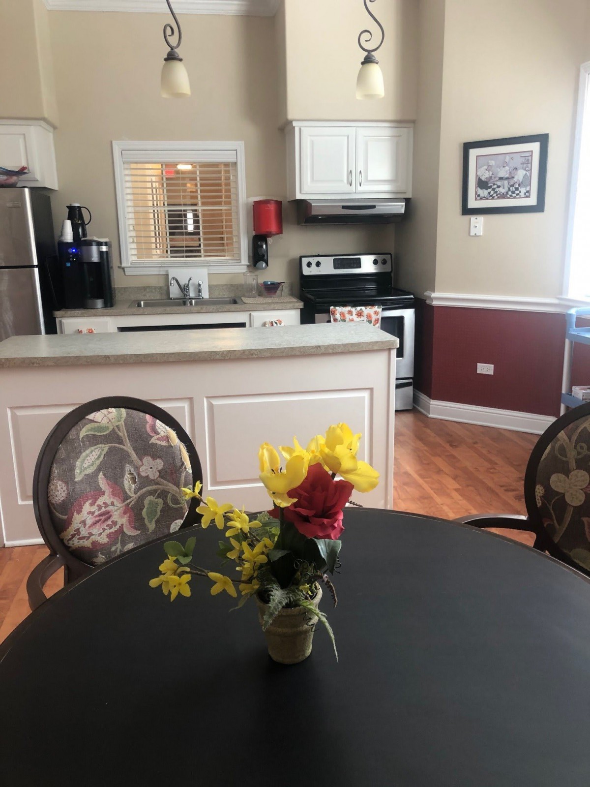 A cozy kitchen and dining area with a table set with flowers in the foreground.