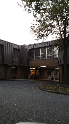 A view of a modern architectural building featuring large windows and a metal roof.
