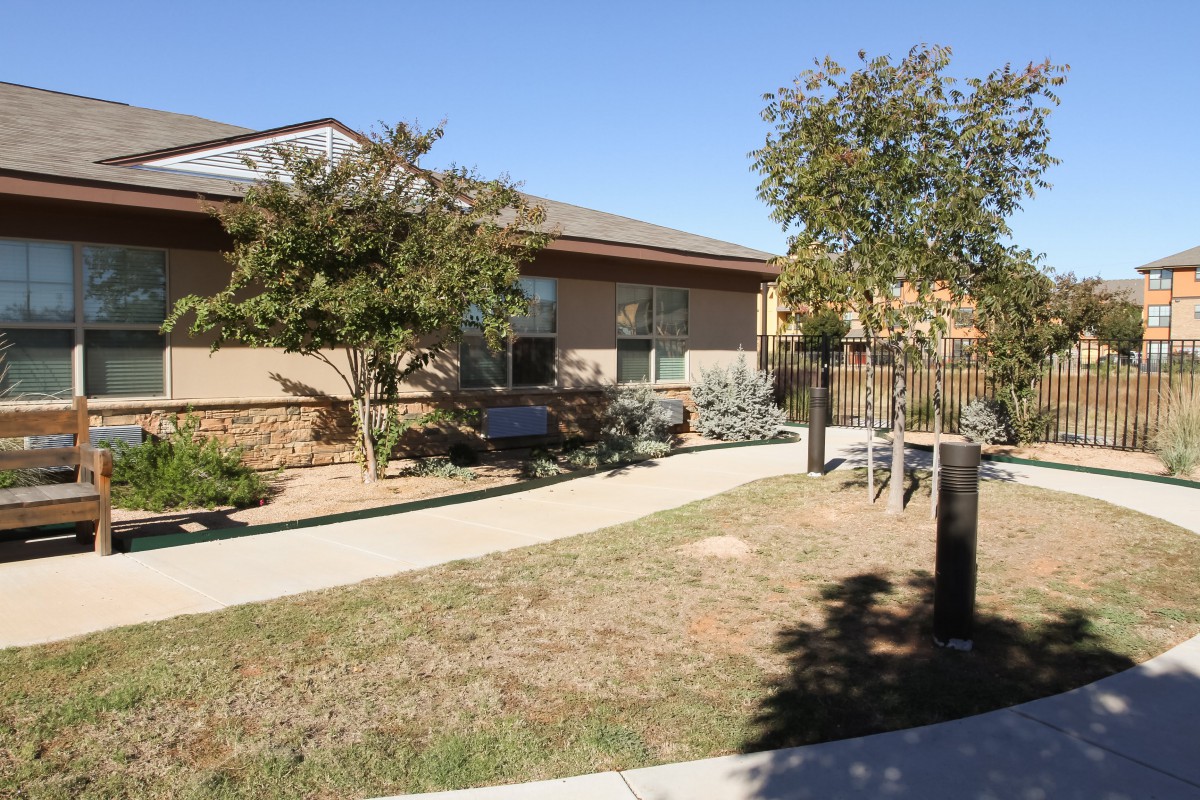 A residential home with a front yard and pathway under a clear blue sky.