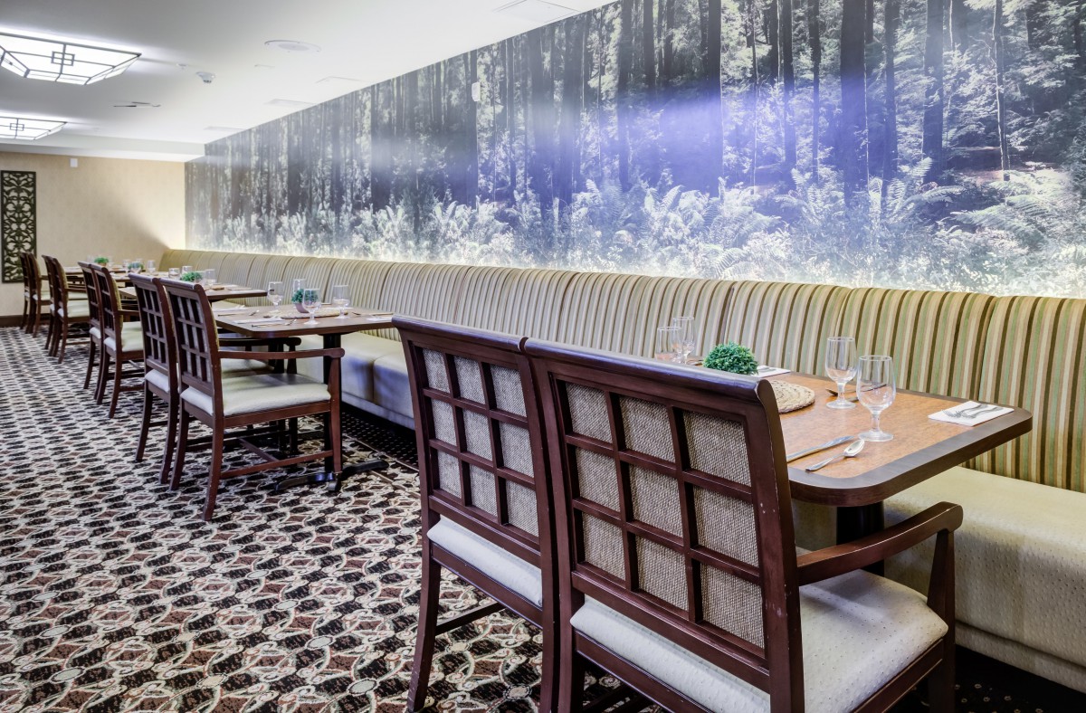 A chic restaurant dining area with stylish chairs and tables, featuring a large wall mural and patterned floor tiles.