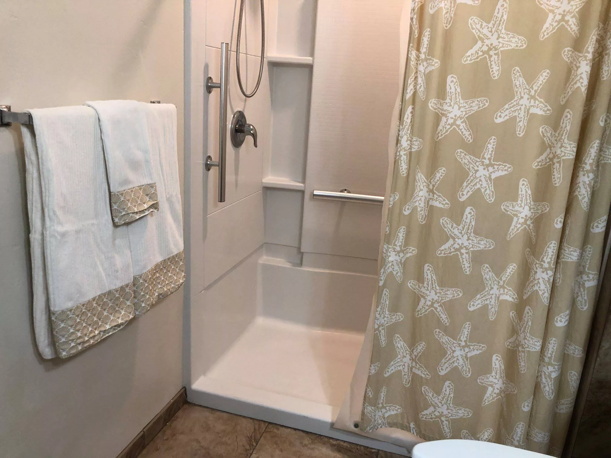 A neatly arranged bathroom featuring a shower with a starfish-patterned curtain and folded towels.
