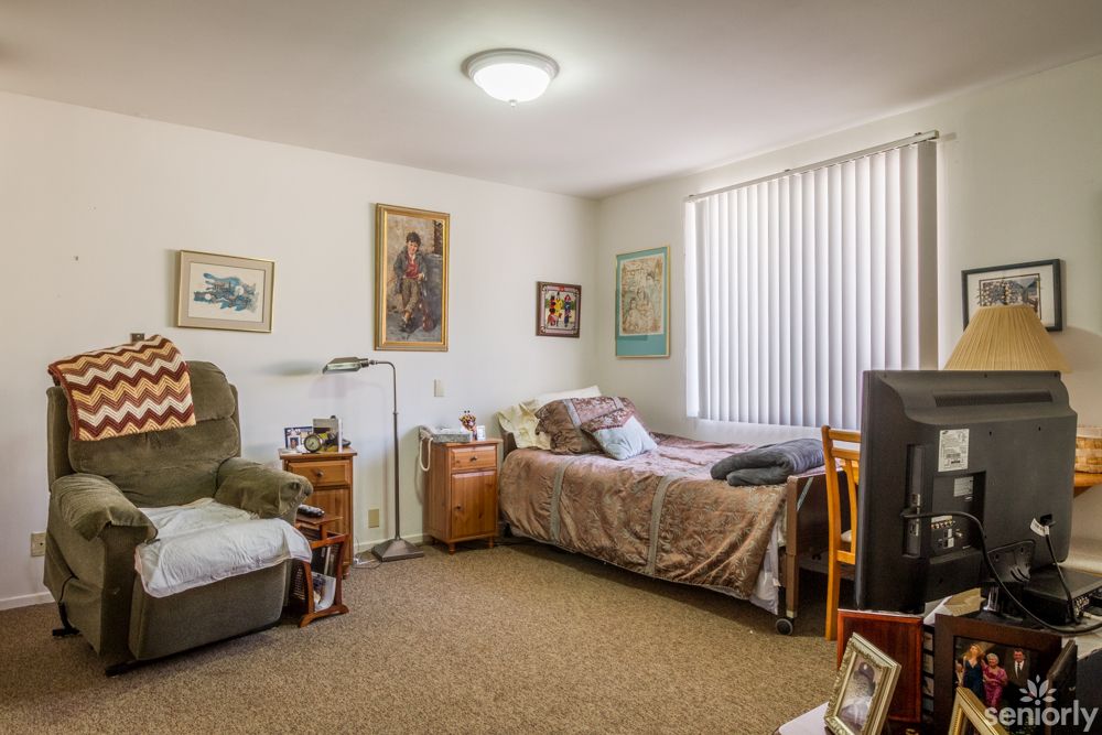 A cozy bedroom with a bed, armchair, and various decor items.