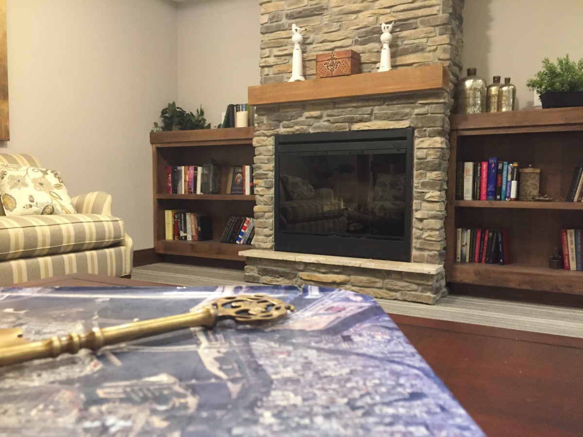 A cozy living room with a stone fireplace, wooden bookshelves, and a decorative table centerpiece.