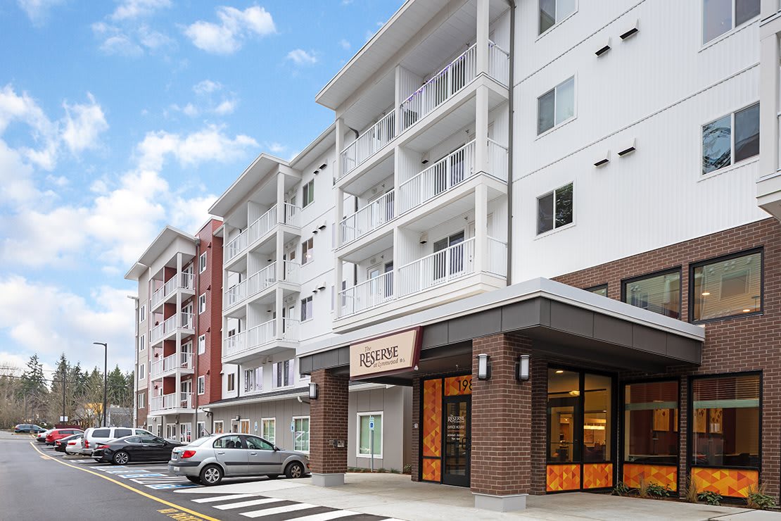 Modern residential apartment building with a parking area in an urban setting.