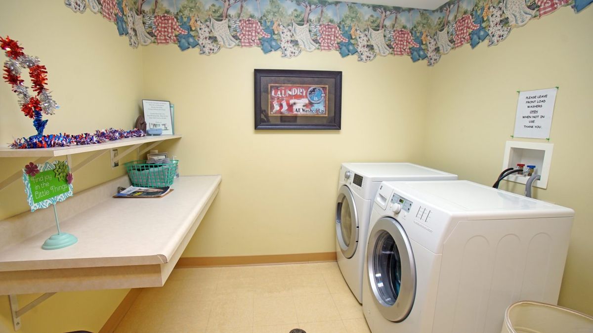 A cozy laundry room with a washing machine, dryer, and decorative floral border.
