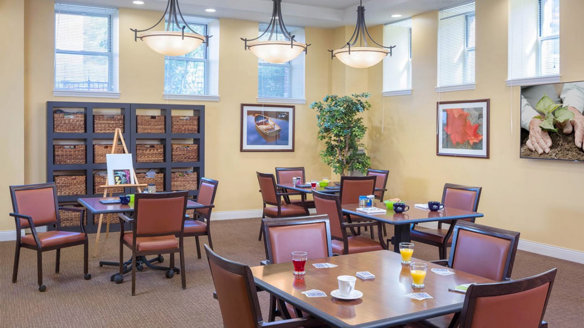 A modern dining room with neatly arranged tables and chairs, adorned with contemporary artwork and elegant lighting.