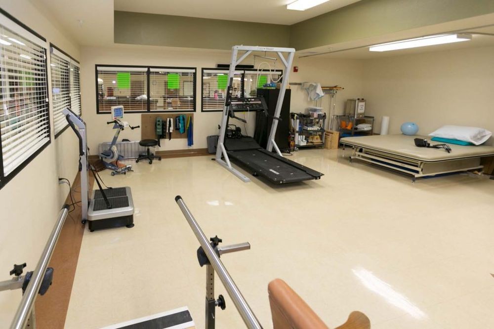 A rehabilitation clinic with exercise equipment, including a treadmill and therapy tools.