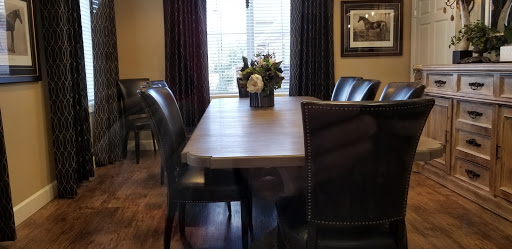 A cozy dining room featuring a wooden table, leather chairs, and a floral centerpiece.