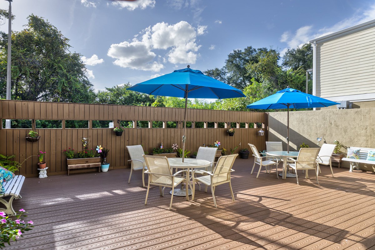 A sunny outdoor patio with tables, chairs, and blue umbrellas.