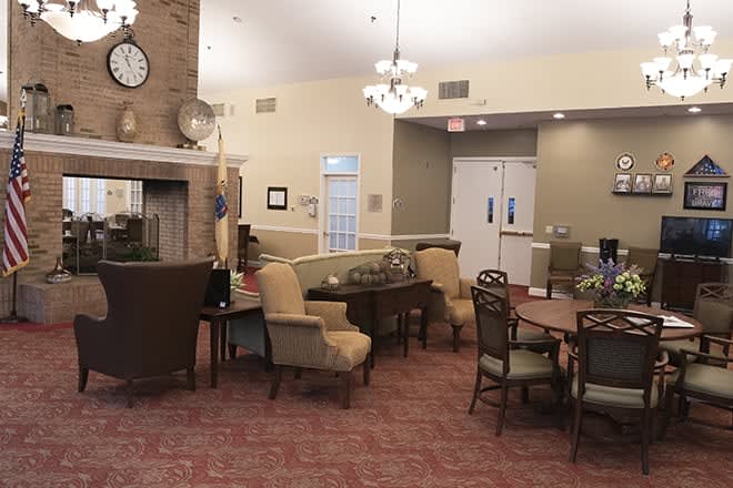 A comfortable living room interior featuring a fireplace, multiple seating areas, and elegant chandeliers.
