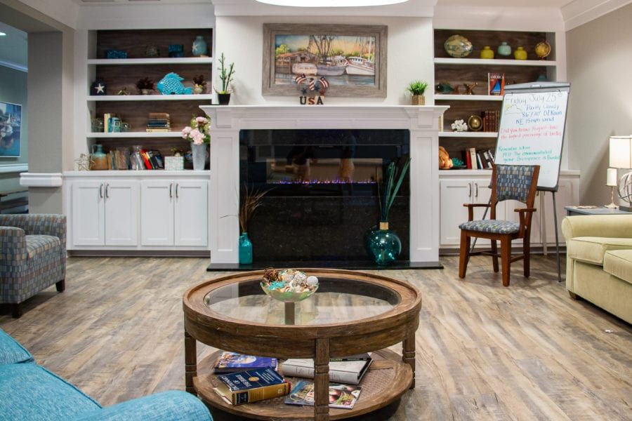 A cozy living room with a central fireplace, surrounded by bookshelves and a round coffee table.