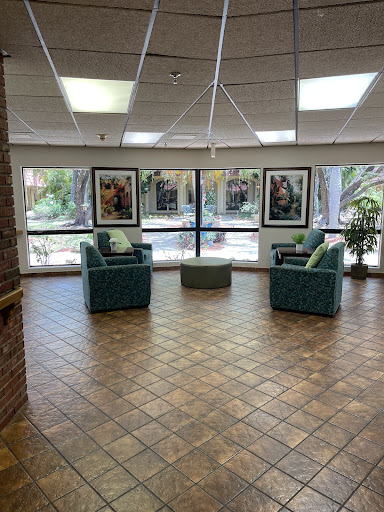 A cozy seating area in a well-lit lobby featuring artwork and views of the outdoors.
