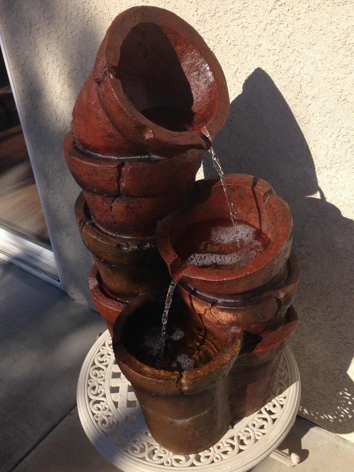 A vintage-style ceramic fountain with water cascading through stacked pots.