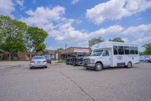 Vehicles parked in a lot outside a commercial building under a partly cloudy sky.
