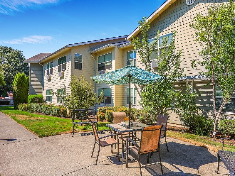 A stylish apartment complex with outdoor seating on a sunny day.