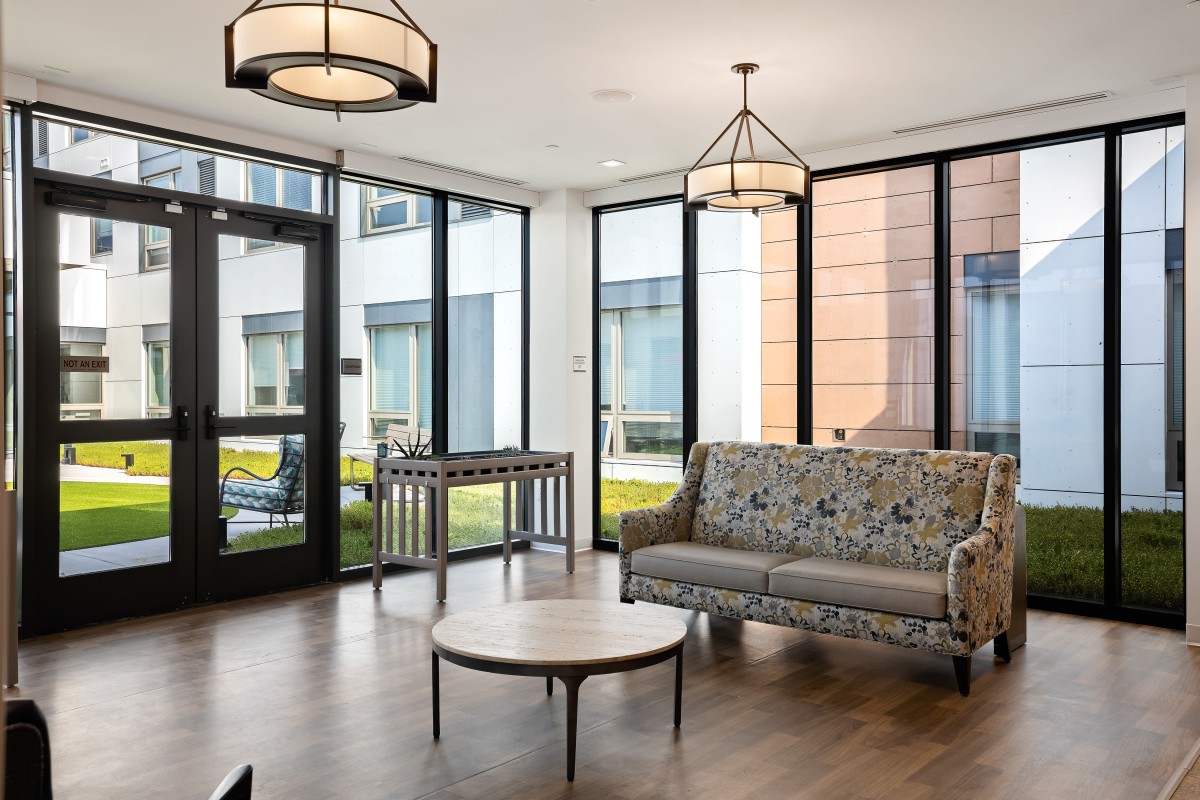 A modern living room with large windows, cozy sofa, and stylish lighting.