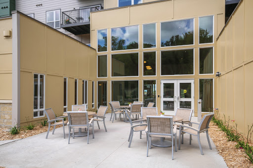A modern outdoor seating area featuring multiple tables and chairs, surrounded by large glass windows.