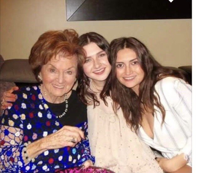 Three women smiling together while seated.