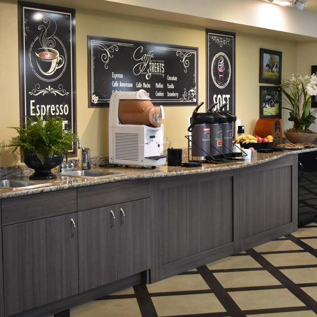 A modern coffee station with various beverage dispensers and decorative signs.