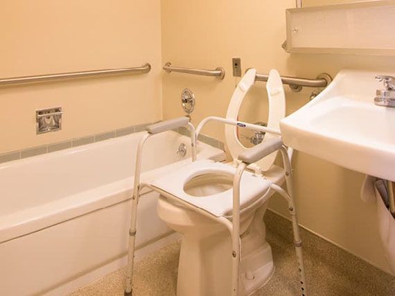 An accessible bathroom with safety features including grab bars and a toilet frame for support.