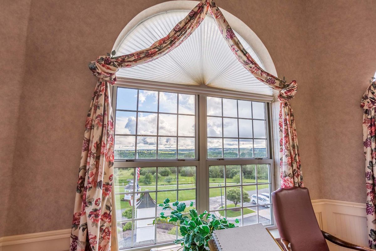 A scenic view through a large window adorned with floral curtains, showcasing a bright and inviting interior space.