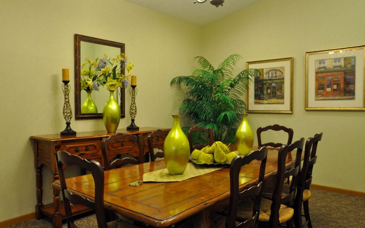 A stylish dining room with wooden furniture and green decorative elements.