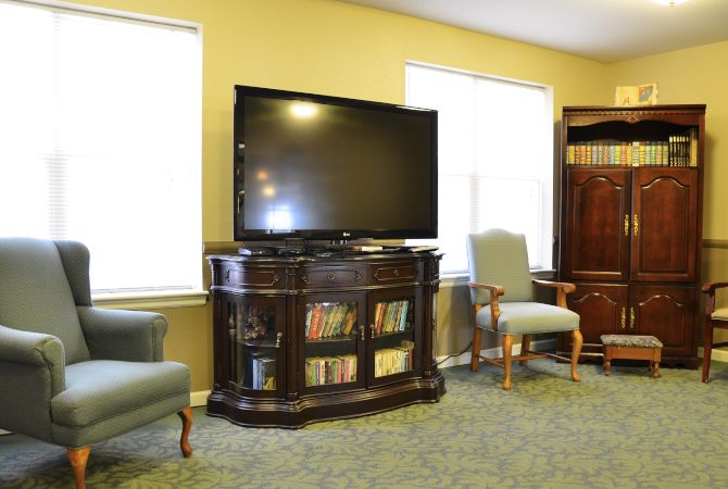 A cozy living room with a television, bookshelf, and comfortable seating.