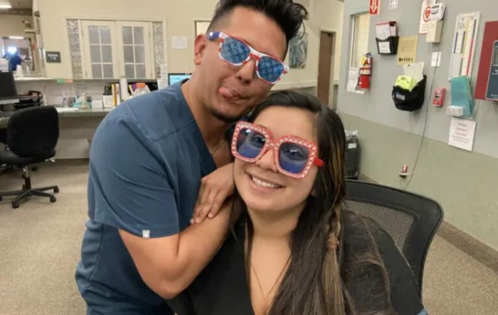 Two friends having fun wearing colorful sunglasses indoors.